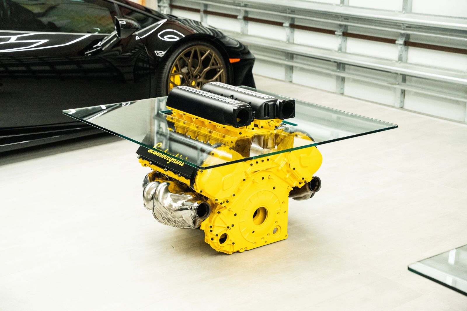 Yellow Lamborghini engine coffee table with black valve covers under a square glass top