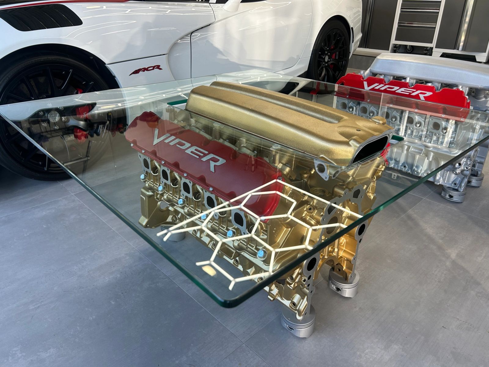 Viper V10 engine table with a gold block and red Viper valve covers under glass